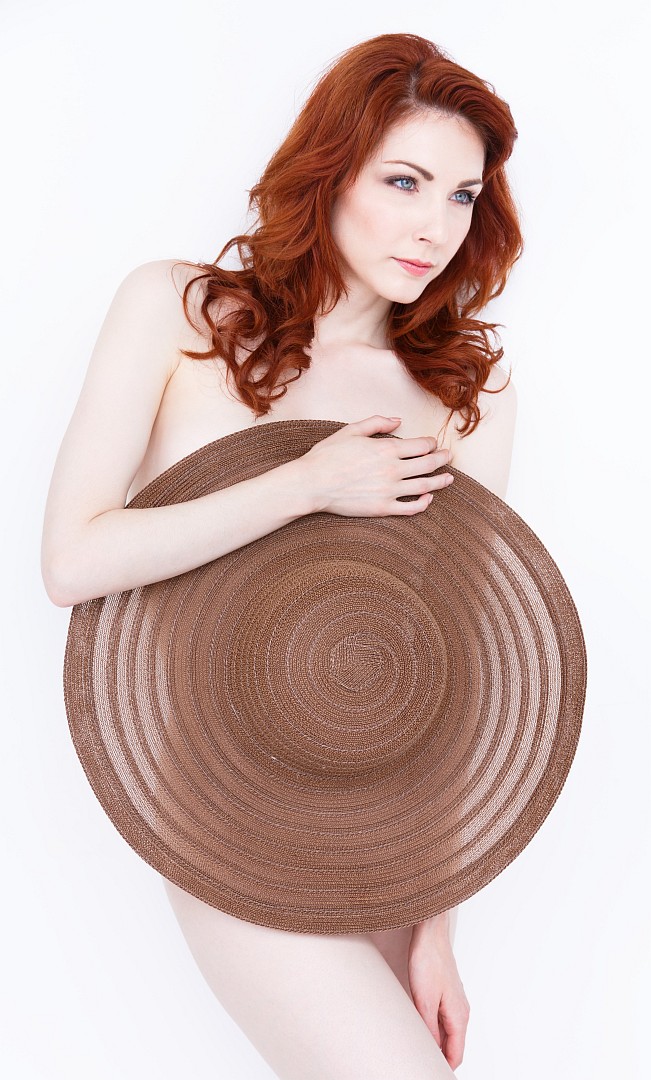 Redhead covering herself with a summer hat